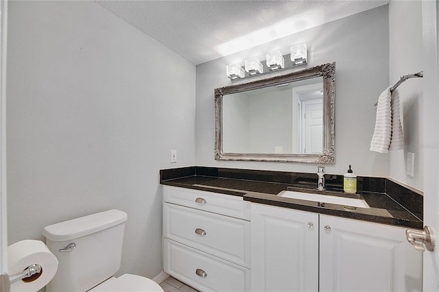 bathroom with vanity, toilet, and a textured ceiling