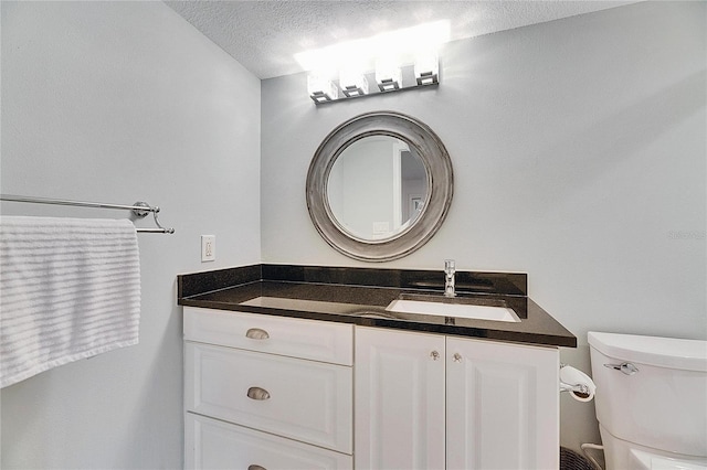 bathroom with vanity, toilet, and a textured ceiling