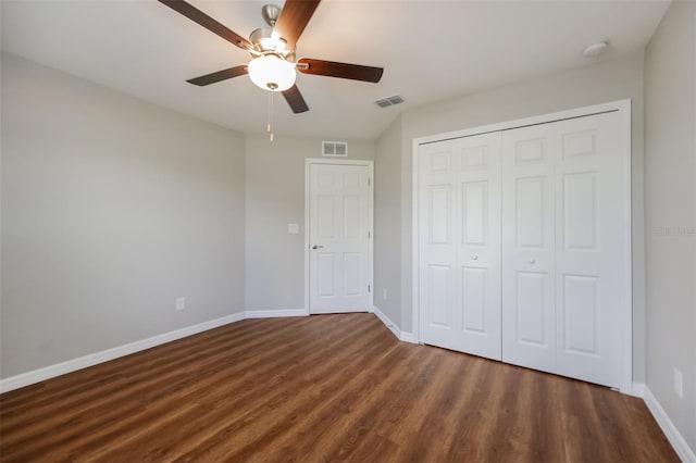 unfurnished bedroom featuring dark wood-type flooring, a closet, and ceiling fan