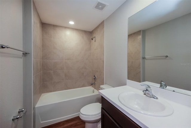 full bathroom with vanity, hardwood / wood-style floors, tiled shower / bath, and toilet