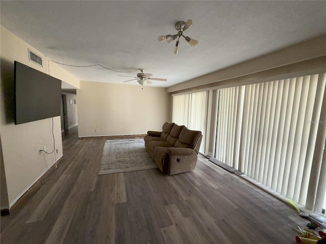 unfurnished living room featuring dark wood-type flooring, visible vents, ceiling fan, and a textured ceiling