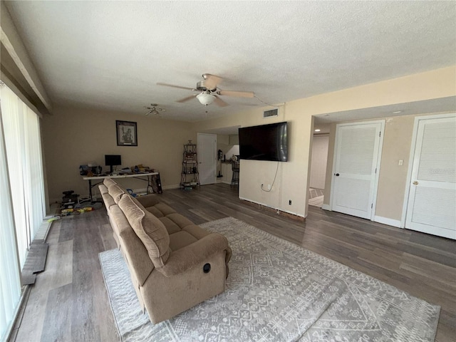 living room with a textured ceiling, visible vents, and wood finished floors