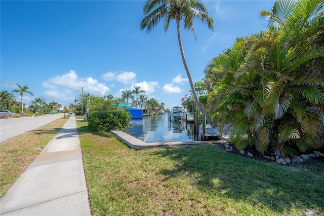 view of dock with a water view and a yard