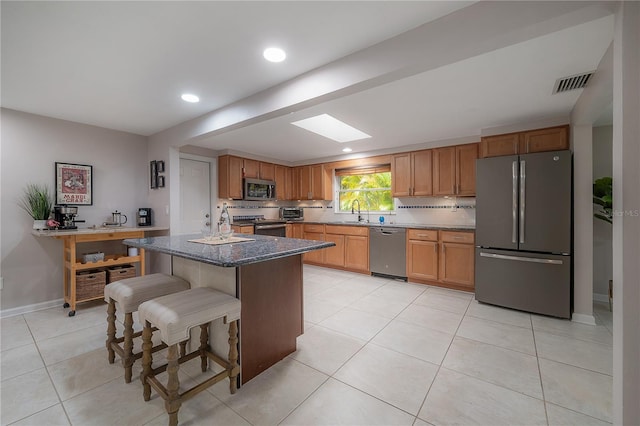 kitchen with tasteful backsplash, a center island, dark stone countertops, light tile patterned floors, and stainless steel appliances