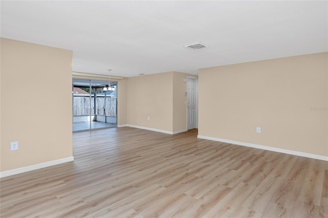 spare room with a notable chandelier and light hardwood / wood-style flooring