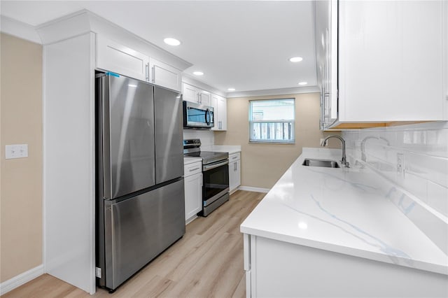 kitchen featuring sink, white cabinets, light stone counters, stainless steel appliances, and light hardwood / wood-style flooring