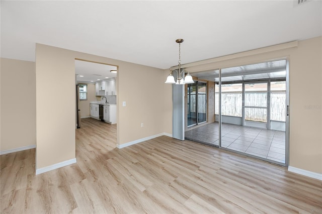 unfurnished dining area featuring sink, a notable chandelier, and light hardwood / wood-style flooring