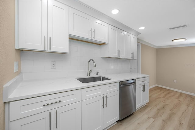 kitchen featuring sink, light hardwood / wood-style flooring, white cabinetry, tasteful backsplash, and stainless steel dishwasher