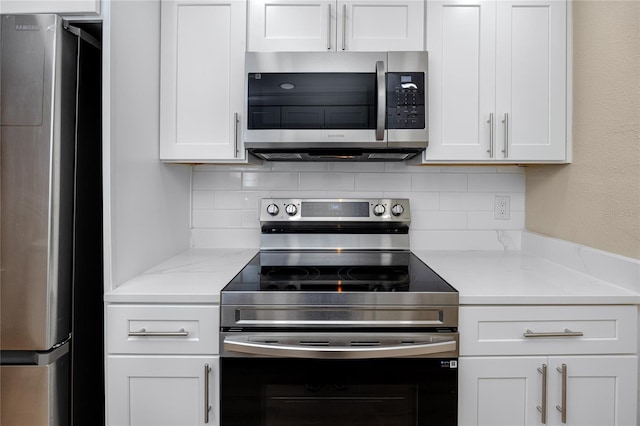 kitchen with light stone countertops, white cabinetry, appliances with stainless steel finishes, and backsplash