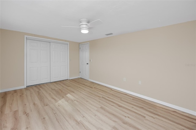 unfurnished bedroom featuring ceiling fan, light hardwood / wood-style floors, and a closet