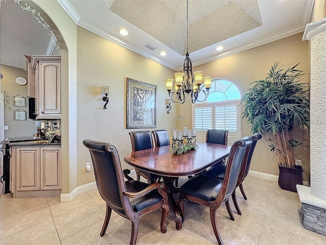 tiled dining room with an inviting chandelier, ornamental molding, and a raised ceiling