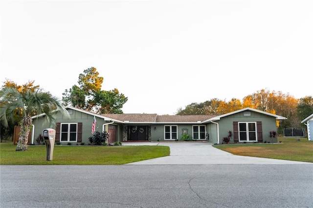 ranch-style home featuring driveway and a front lawn