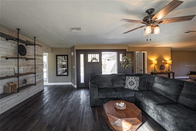 unfurnished living room with baseboards, visible vents, dark wood finished floors, and a textured ceiling