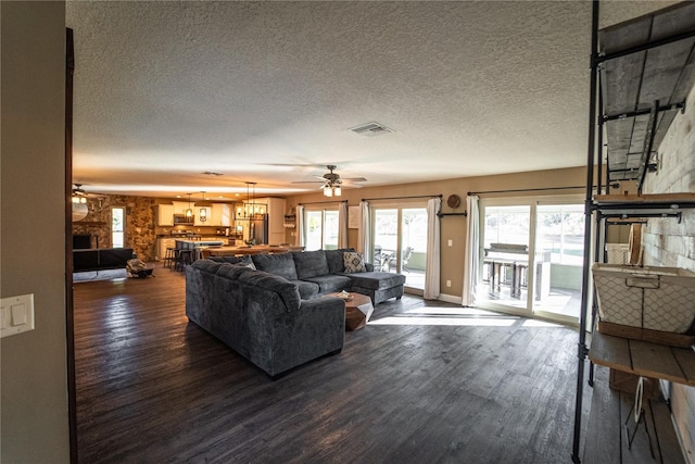 living area with visible vents, dark wood finished floors, a textured ceiling, and ceiling fan