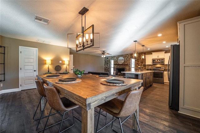 dining room with ceiling fan, a fireplace, dark wood finished floors, and visible vents