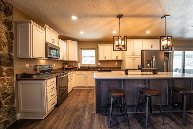 kitchen with stainless steel appliances, decorative light fixtures, a sink, and white cabinetry