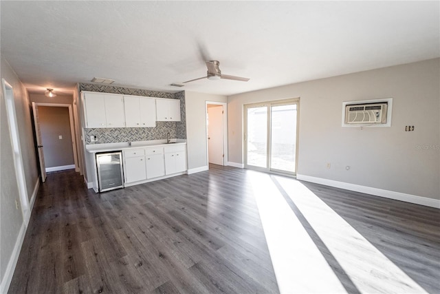 kitchen with beverage cooler, white cabinets, light countertops, an AC wall unit, and backsplash