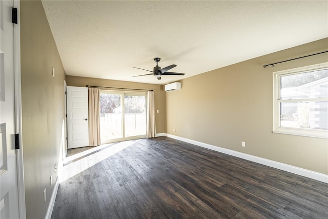 unfurnished room with a textured ceiling, a ceiling fan, baseboards, a wall mounted AC, and dark wood-style floors