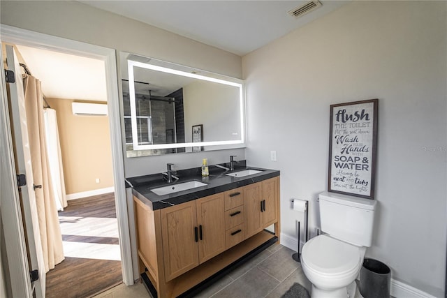 bathroom featuring double vanity, visible vents, a sink, and a wall mounted air conditioner