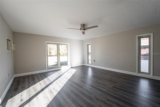 empty room with ceiling fan, plenty of natural light, dark wood finished floors, and baseboards