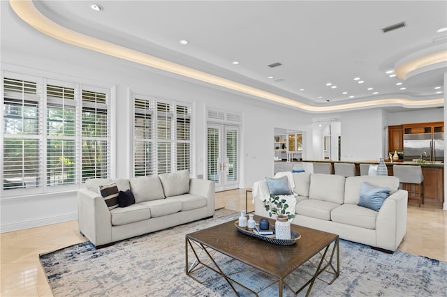 tiled living room featuring a raised ceiling and french doors