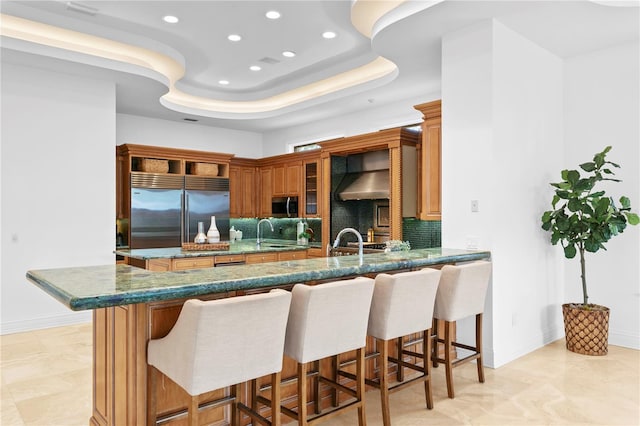 kitchen featuring appliances with stainless steel finishes, sink, a breakfast bar area, decorative backsplash, and kitchen peninsula