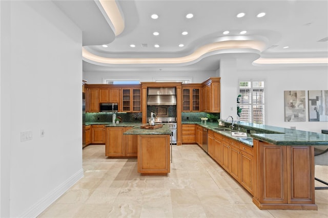 kitchen with a kitchen island, a raised ceiling, kitchen peninsula, and appliances with stainless steel finishes