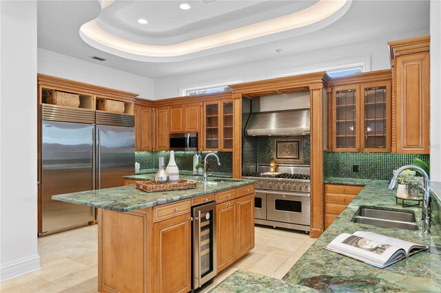 kitchen with high quality appliances, sink, beverage cooler, and wall chimney exhaust hood