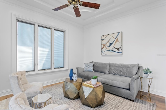 living room with crown molding, a raised ceiling, ceiling fan, and light wood-type flooring