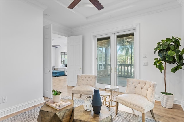 living area with wood-type flooring, ceiling fan, and crown molding