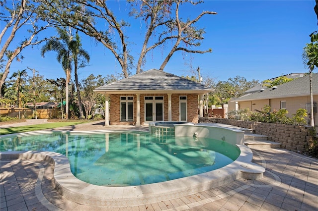 view of swimming pool featuring an in ground hot tub, an outbuilding, and a patio area