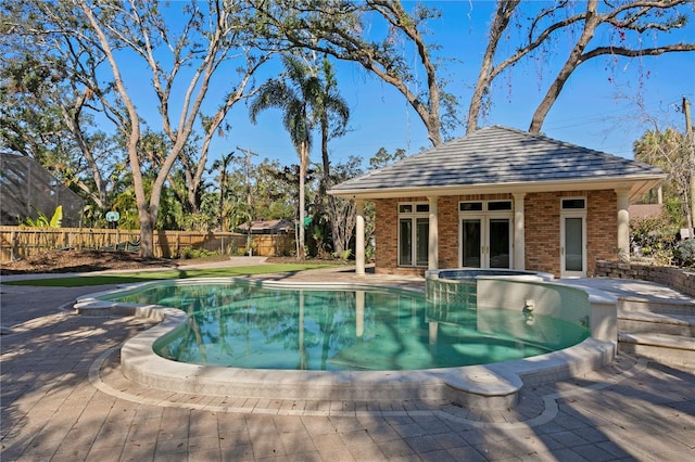 view of pool featuring an outbuilding, an in ground hot tub, and a patio