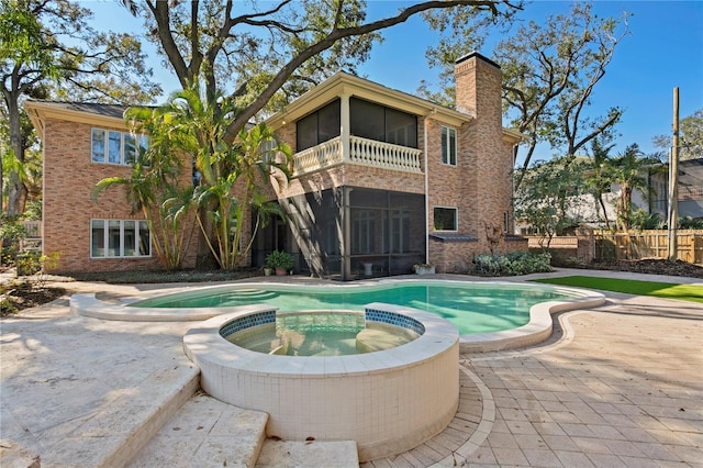 view of pool with an in ground hot tub, a sunroom, and a patio