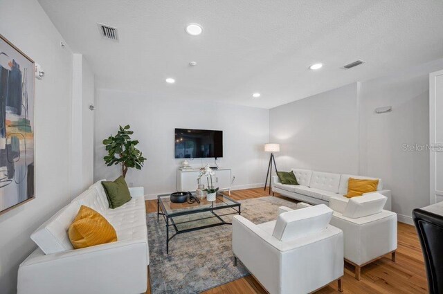 living area with baseboards, visible vents, wood finished floors, and recessed lighting