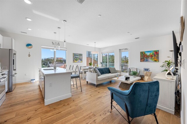 living room with baseboards, light wood finished floors, visible vents, and recessed lighting