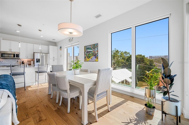 dining area with light wood finished floors and visible vents