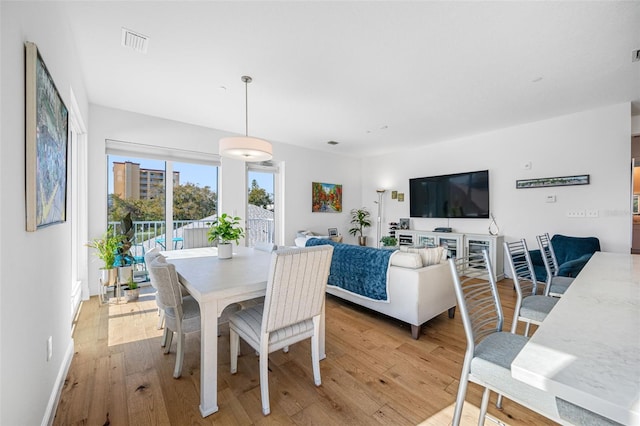 dining space featuring light wood-style floors, baseboards, and visible vents