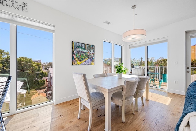 dining area featuring light wood-style flooring, visible vents, and baseboards