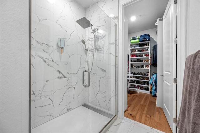 bathroom featuring marble finish floor, a marble finish shower, and a walk in closet