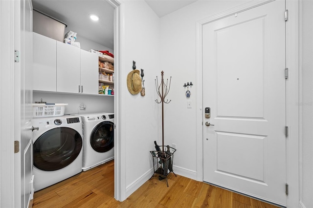 washroom featuring light wood finished floors, baseboards, separate washer and dryer, and cabinet space