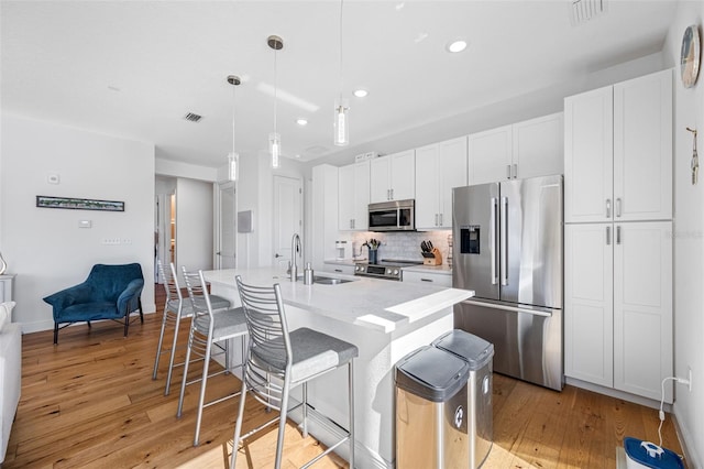 644 3rd Ave S Unit 305, Saint Petersburg, FL 33701 - kitchen featuring stainless steel appliances, backsplash, white cabinetry, an island with sink, and a kitchen bar