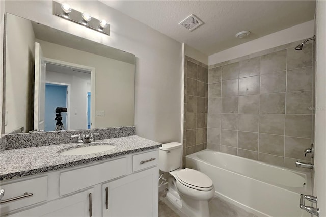 full bathroom featuring tiled shower / bath, vanity, a textured ceiling, and toilet