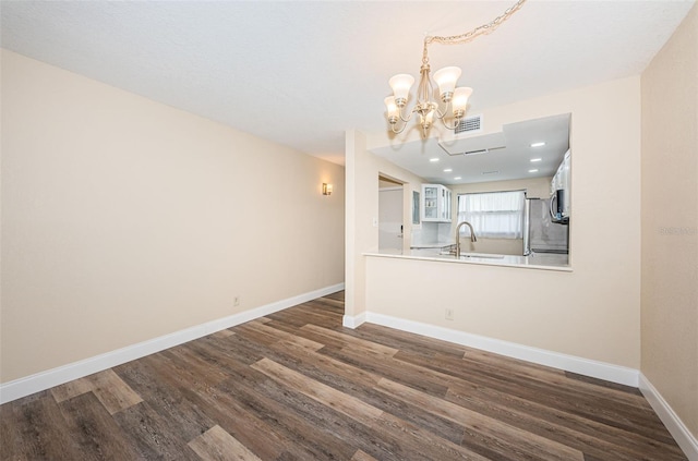 unfurnished dining area featuring sink, dark wood-type flooring, and a chandelier