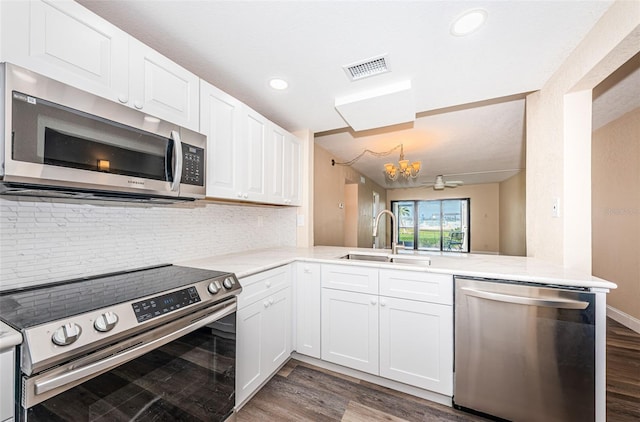 kitchen featuring sink, appliances with stainless steel finishes, white cabinetry, dark hardwood / wood-style floors, and kitchen peninsula