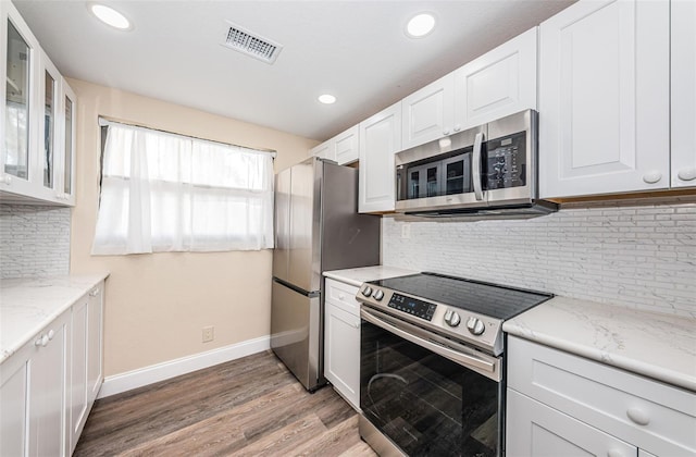 kitchen with light stone countertops, white cabinets, and appliances with stainless steel finishes