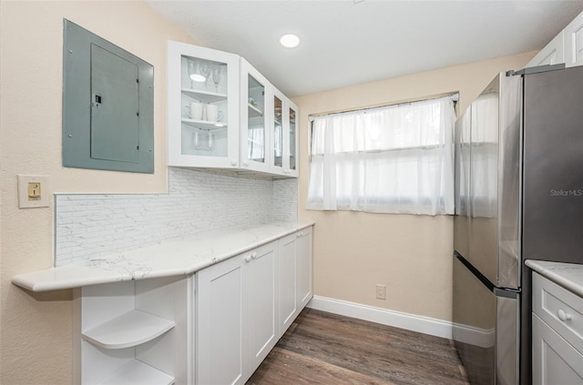 kitchen featuring stainless steel refrigerator, backsplash, dark hardwood / wood-style flooring, white cabinets, and electric panel