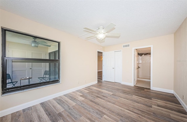 unfurnished bedroom with wood-type flooring, ceiling fan, a textured ceiling, and ensuite bath