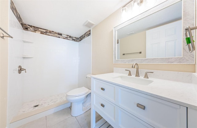 bathroom featuring vanity, a tile shower, tile patterned floors, and toilet