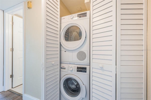 laundry room featuring wood-type flooring and stacked washing maching and dryer