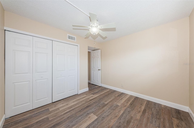 unfurnished bedroom featuring ceiling fan, dark wood-type flooring, a textured ceiling, and a closet